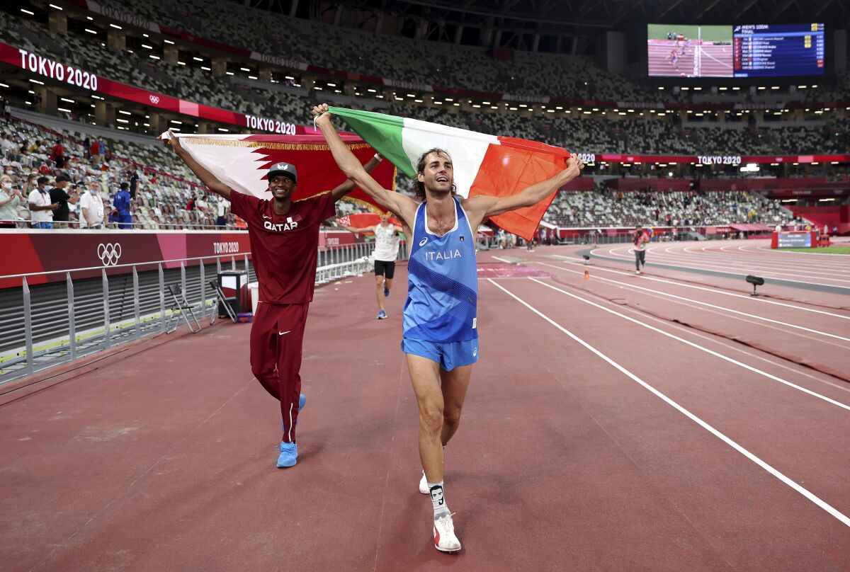Gold medalist Mutaz Barshim, left, of Qatar and silver medalist Gianmarco Tamberi of Italy celebrate on the track after the final of the men's high jump at the 2020 Summer Olympics, Sunday, Aug. 1, 2021, in Tokyo, Japan. (Christian Petersen/Pool Photo via AP)
