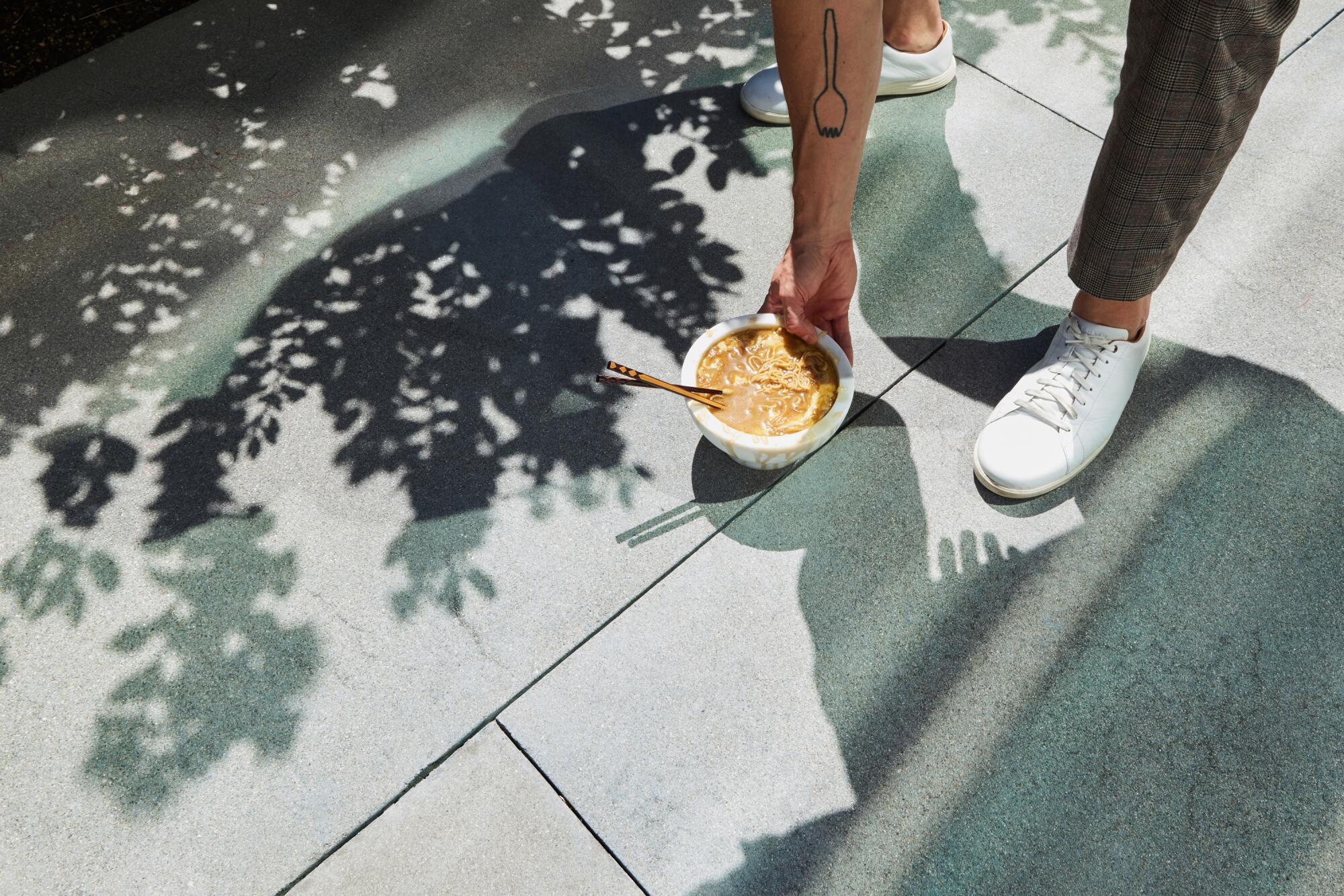 Scherer sets a bowl of French onion ramen on the ground outside.