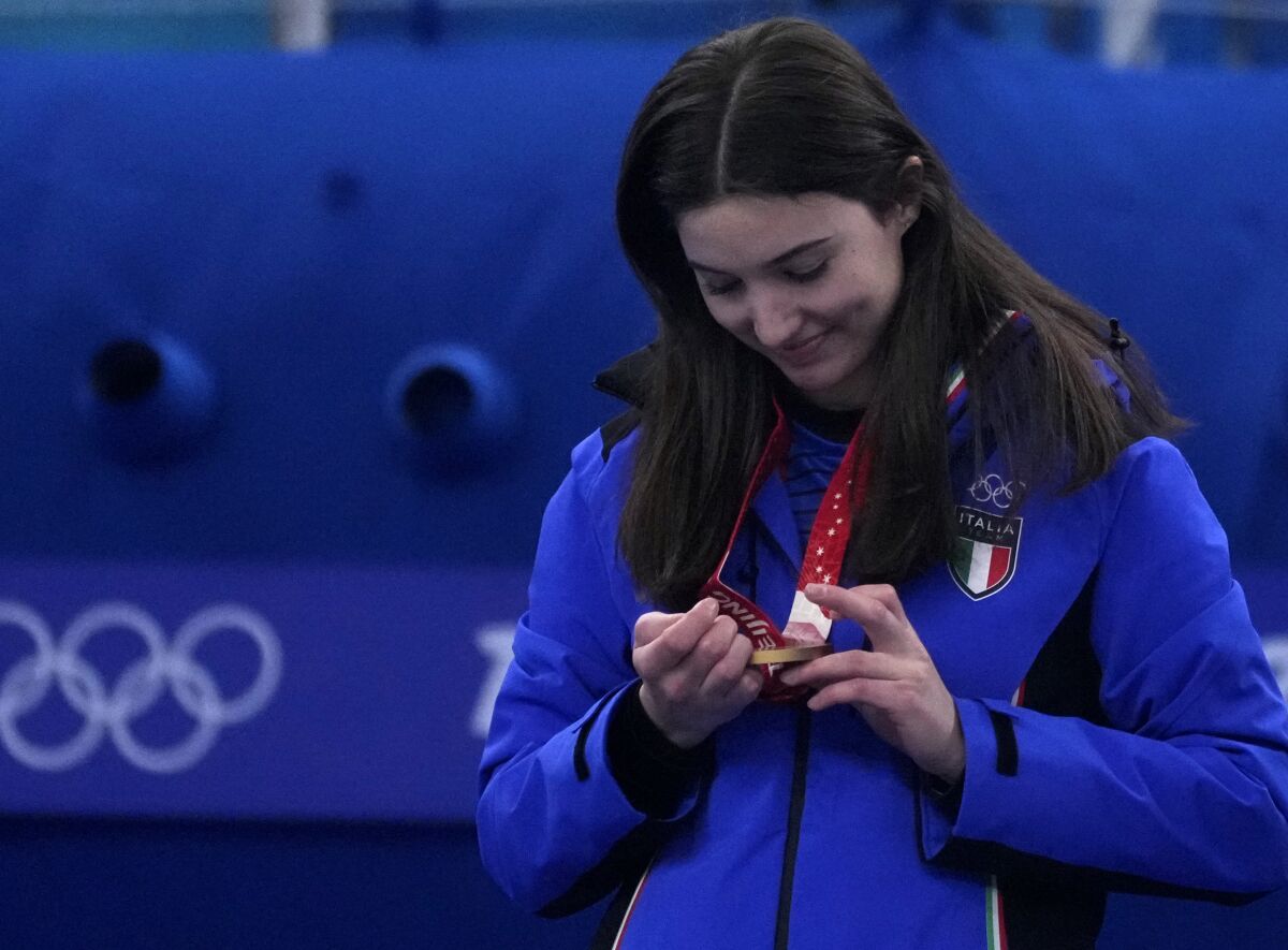 Italy's Stefania Constantini, looks at her gold medal, during the awards ceremony for the mixed doubles curling match against Norway, in the curling venue, at the 2022 Winter Olympics, Tuesday, Feb. 8, 2022, in Beijing. (AP Photo/Nariman El-Mofty)
