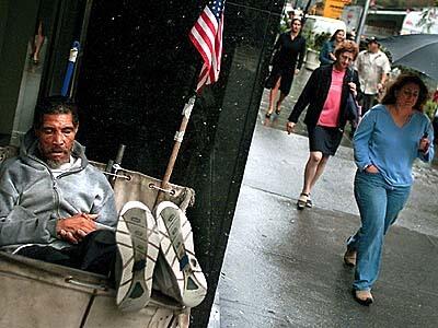 "I was shooting the first day Wall Street reopened and was looking for people reacting to the market taking a dive. I saw this man sleeping. This photo shows that even though he may think the government hasn't helped him, he still loves his country."--Wally Skalij