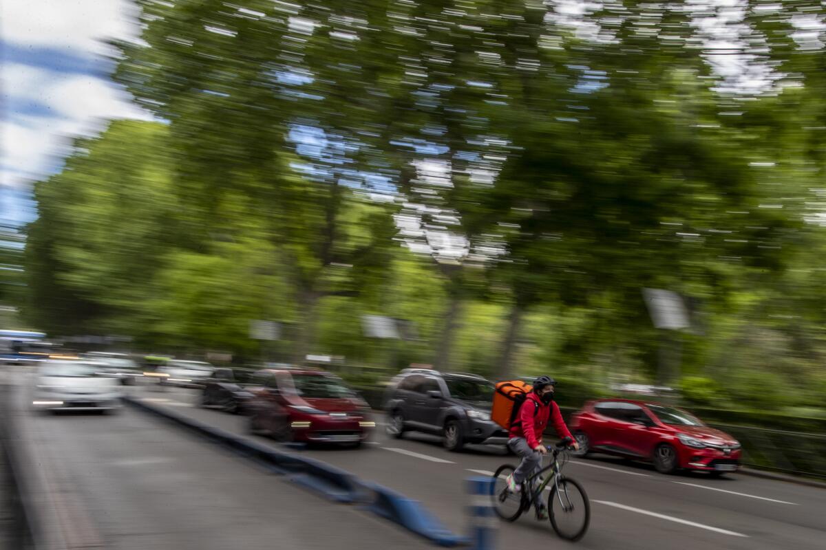 A delivery worker rides his bike in Madrid, Spain, Tuesday, May 11, 2021. 