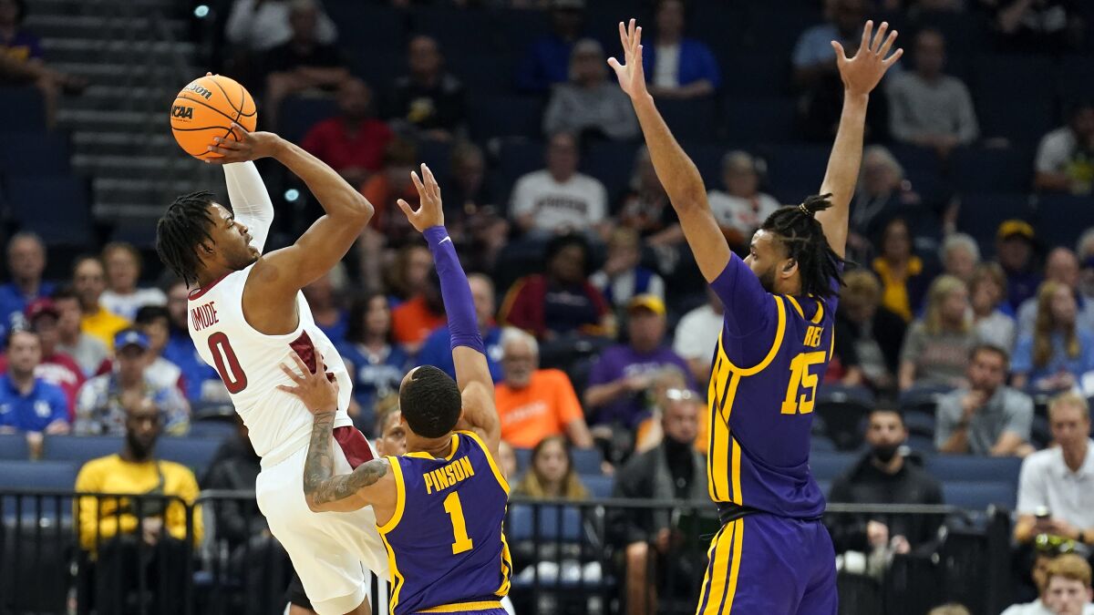 Arkansas guard Stanley Umude (0) shoots over LSU guard Xavier Pinson (1) and center Efton Reid (15) during the first half of an NCAA men's college basketball Southeastern Conference tournament game, Friday, March 11, 2022, in Tampa, Fla. (AP Photo/Chris O'Meara)