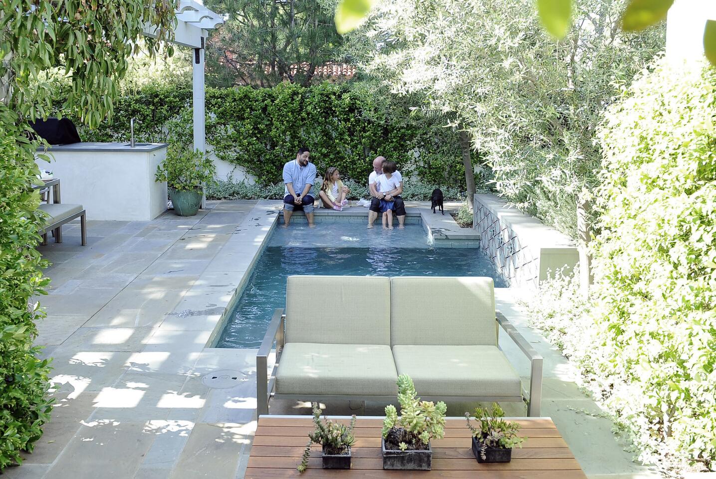 David Collins and partner Joseph Rivas, along with twin daughters Olive and Ella, and dog Coco, relax in their Atwater backyard.