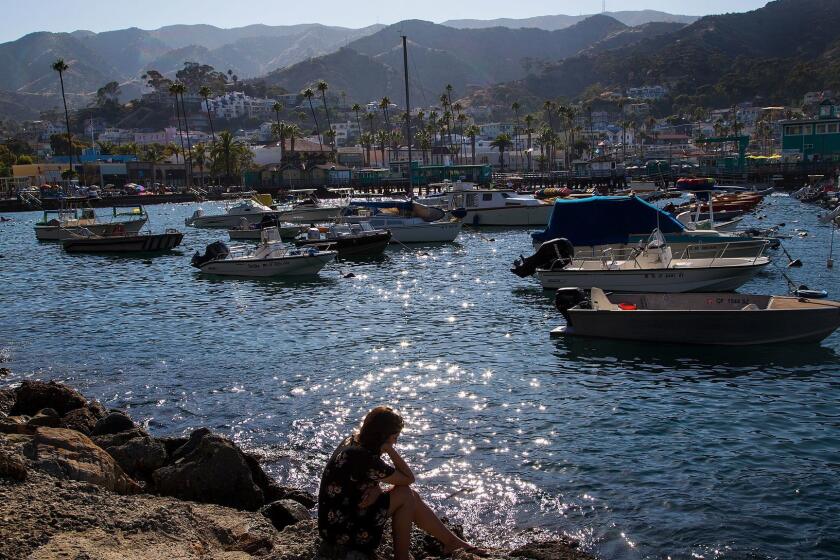 A woman spends a moment in reflection near the shore on Avalon, Calif.