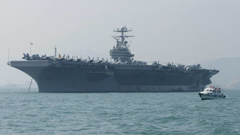 A small boat sails by the U.S. aircraft carrier Abraham Lincoln moored in Hong Kong in this file photo taken Dec. 23, 2004.