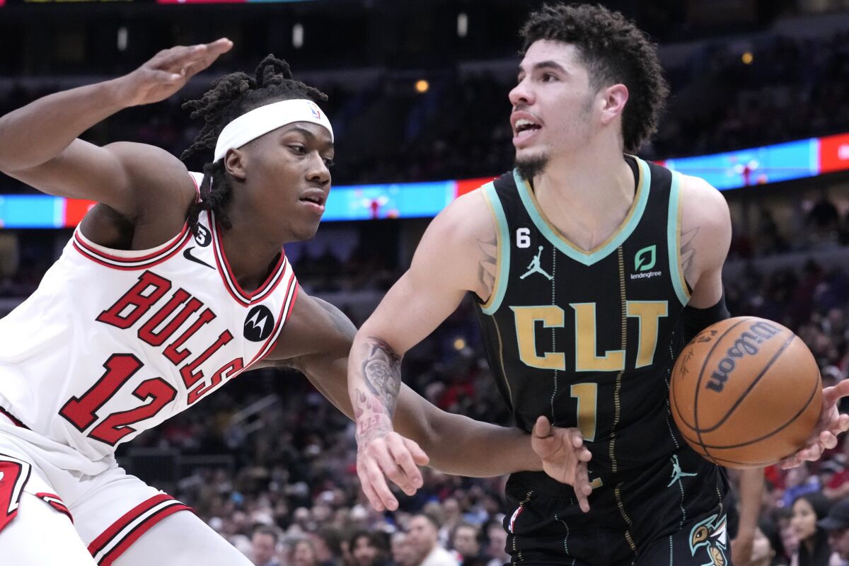 Charlotte Hornets' LaMelo Ball, right, looks to pass as Chicago Bulls' Ayo Dosunmu defends during the first half of an NBA basketball game Thursday, Feb. 2, 2023, in Chicago. (AP Photo/Charles Rex Arbogast)