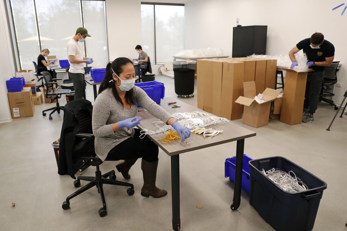 UC Irvine medical students assemble and package face shields produced with 3-D printers and laser cutters at the UCI Beall Applied Innovation Cove in Irvine on Tuesday. The 5,000 face shields will go to UCI Medical Center in Orange.