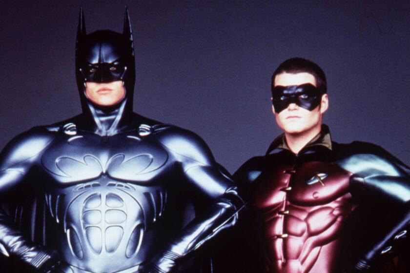 A man in a Batman costume and another man in a Robin costume standing akimbo