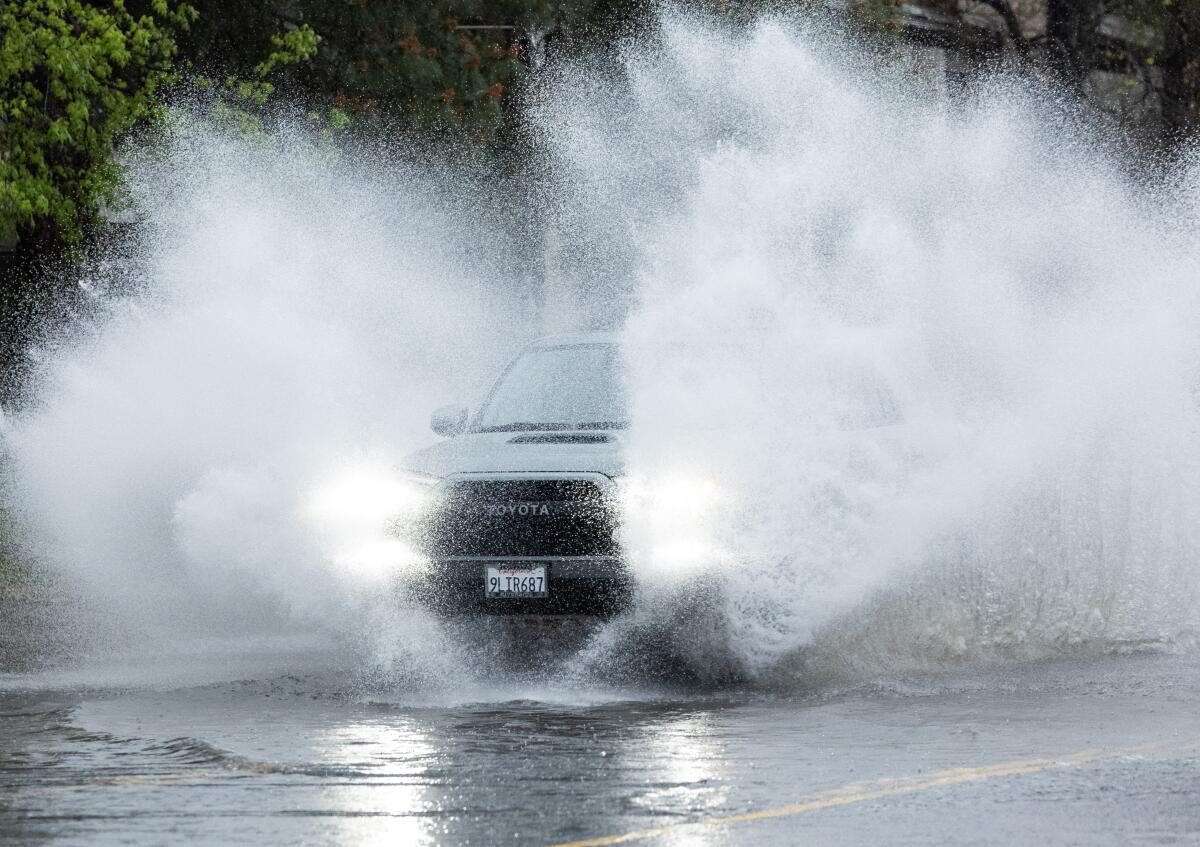 A car splashes through flooded Vanowen Street in North Hollywood, on Saturday, March 30, 2024 during a rainy Easter weekend.