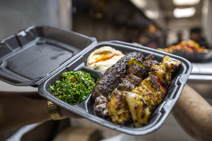 A to-go box of tabbouleh, hummus and kabobs
