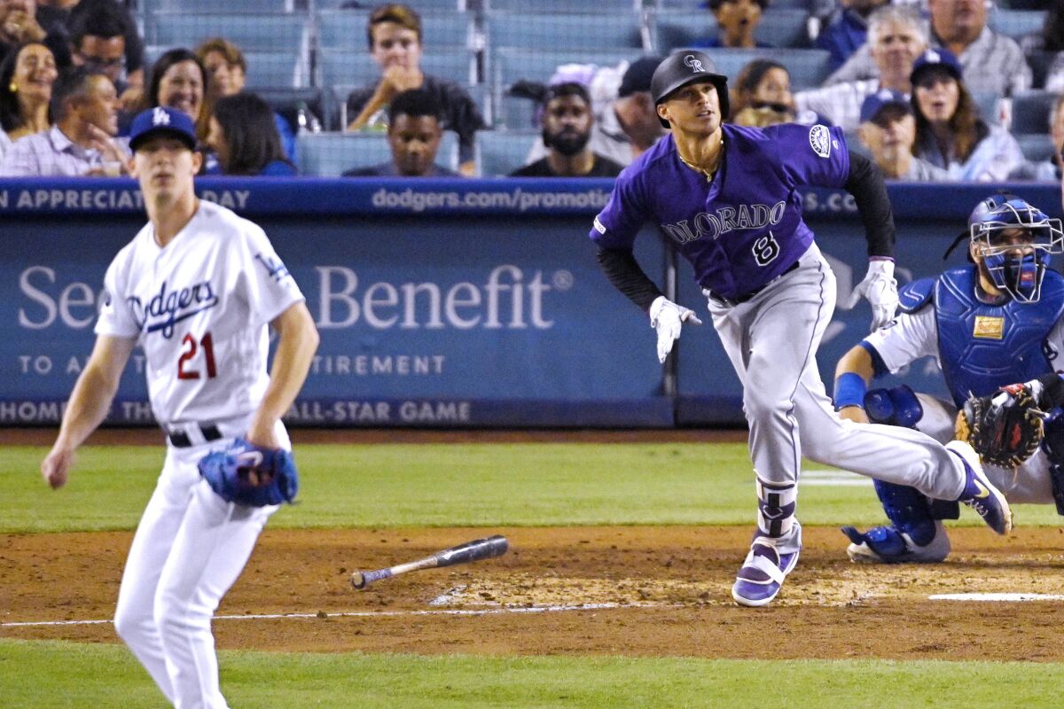 Colorado's Josh Fuentes, center, hits a solo home run off Dodgers pitcher Walker Buehler.