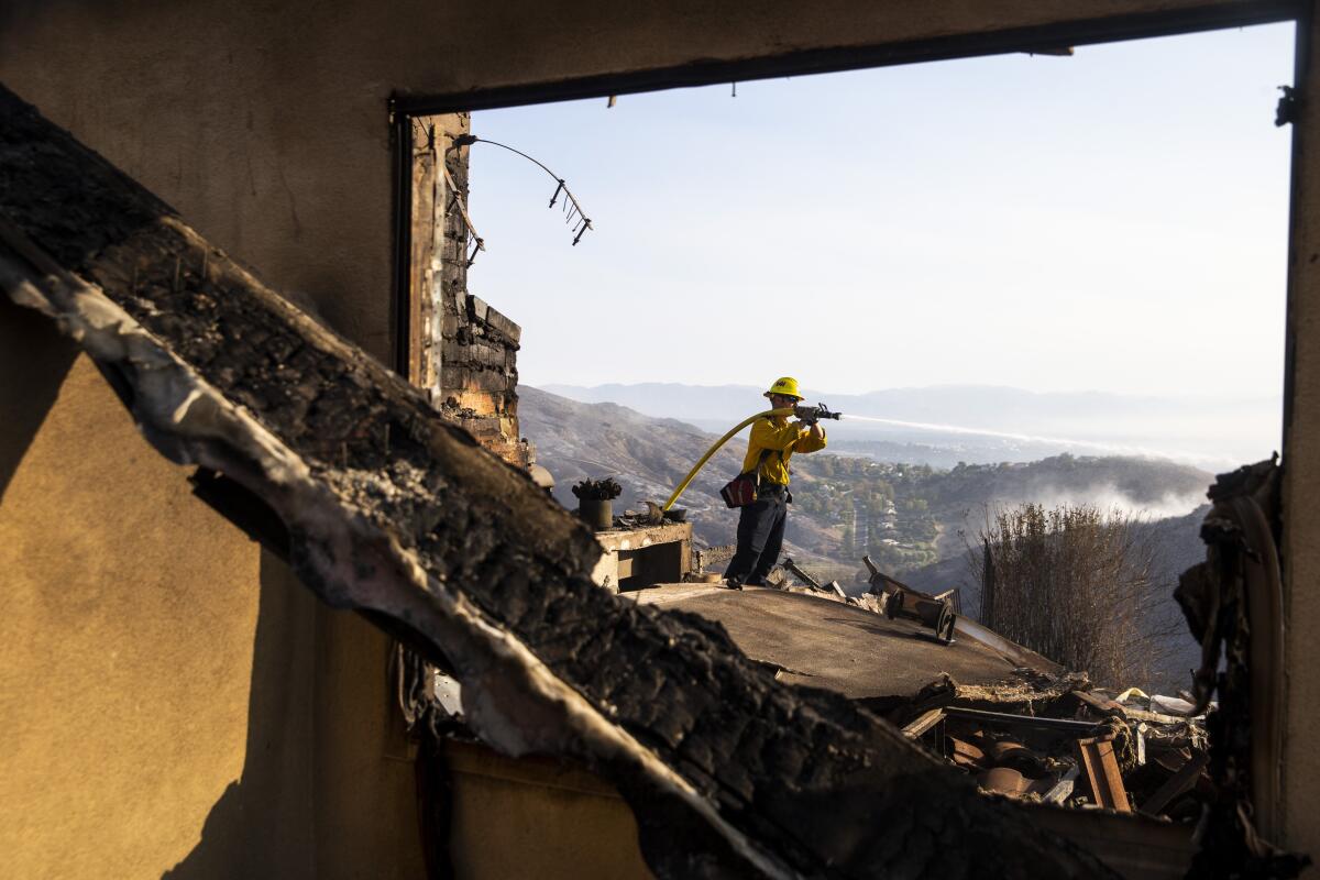 A firefighter is seen through a burned-out window.