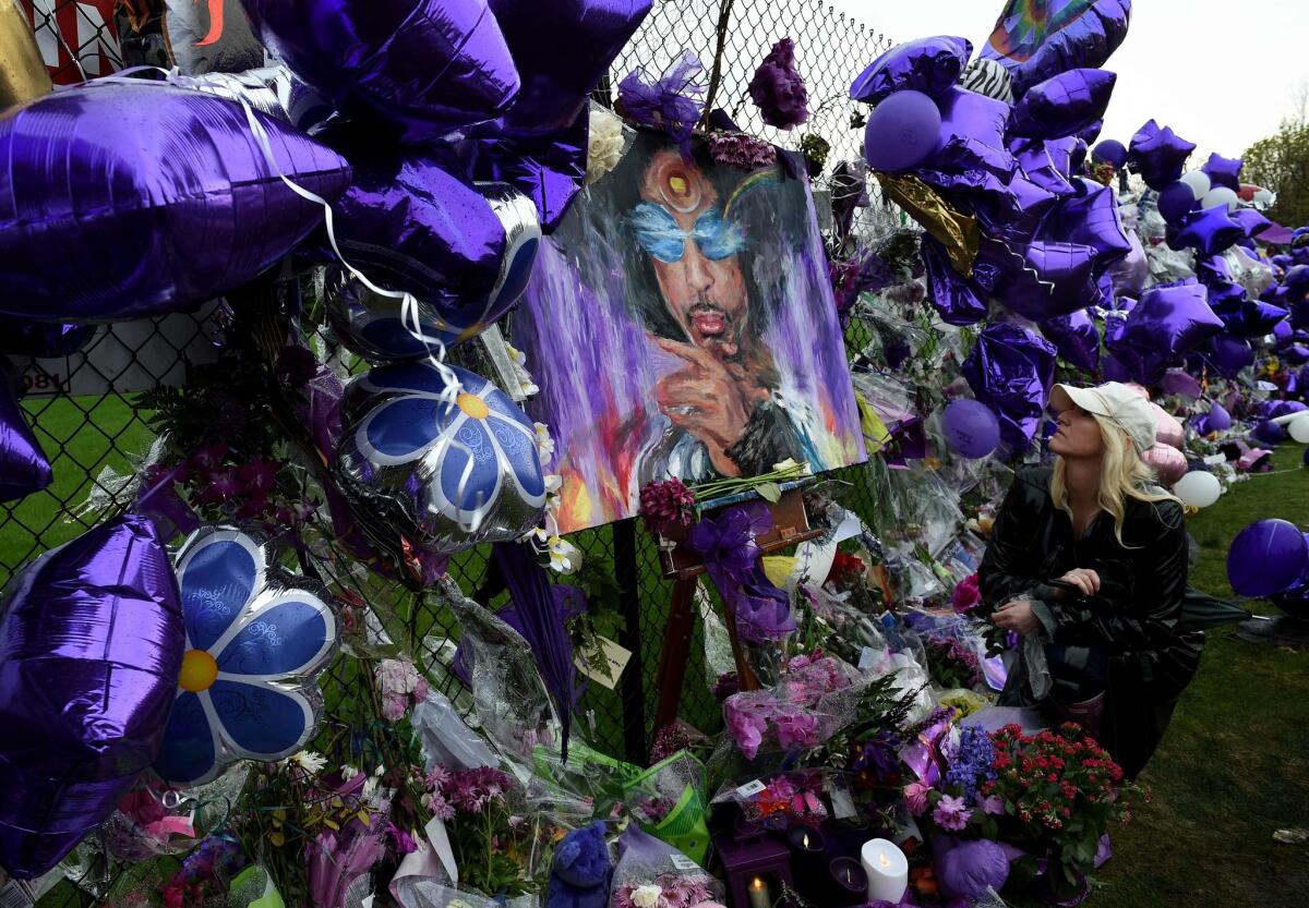 Prince fan Dawn Mitchell leaves a message beside a sea of purple balloons and flowers at a memorial wall outside the Paisley Park compound of music legend Prince, who died suddenly at 57 in Minneapolis, Minn., on April 24, 2016.