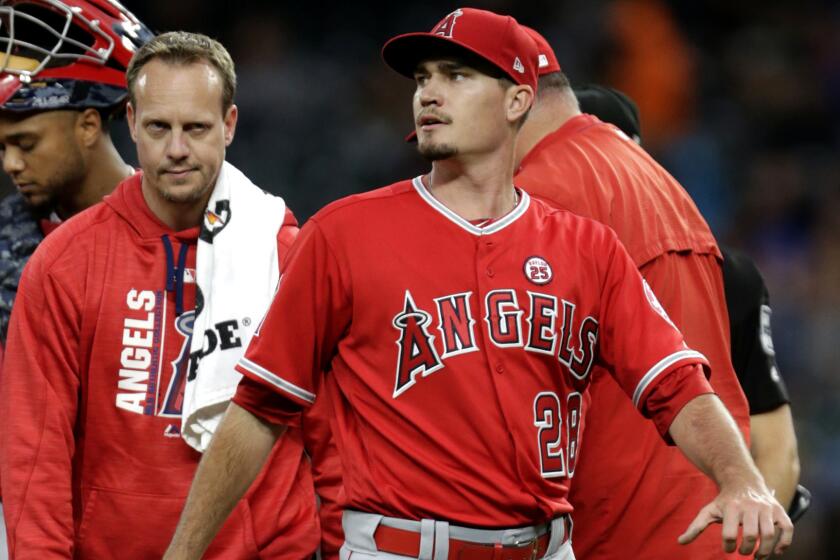Los Angeles Angels starting pitcher Andrew Heaney leaves the baseball game with a trainer during the third inning against the Seattle Mariners, Saturday, Sept. 9, 2017, in Seattle. (AP Photo/John Froschauer)