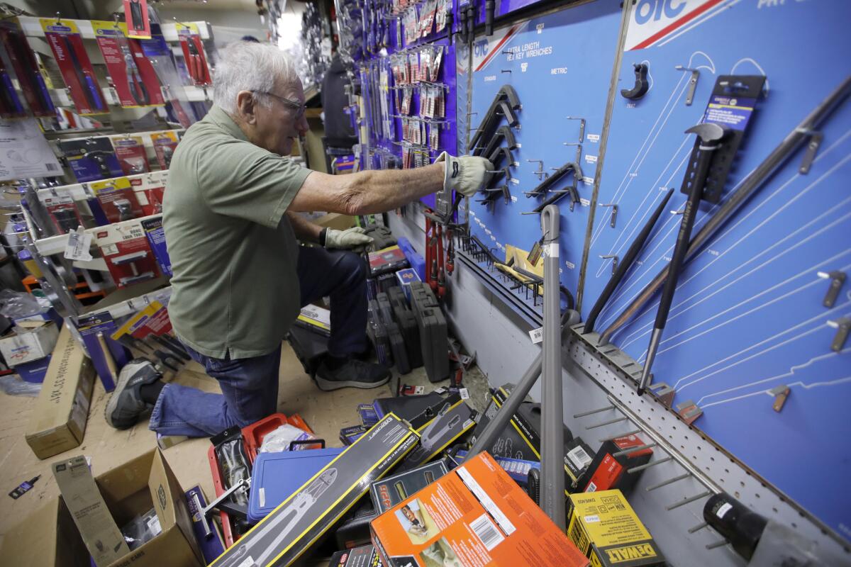George Schauer helps clean up earthquake damage inside a NAPA Auto Parts store in Rio Dell