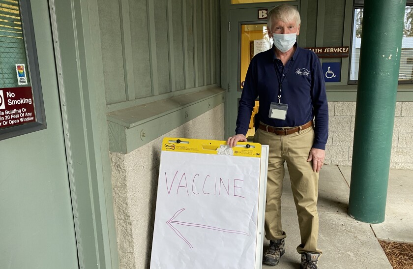 A doctor next to a "Vaccine" sign