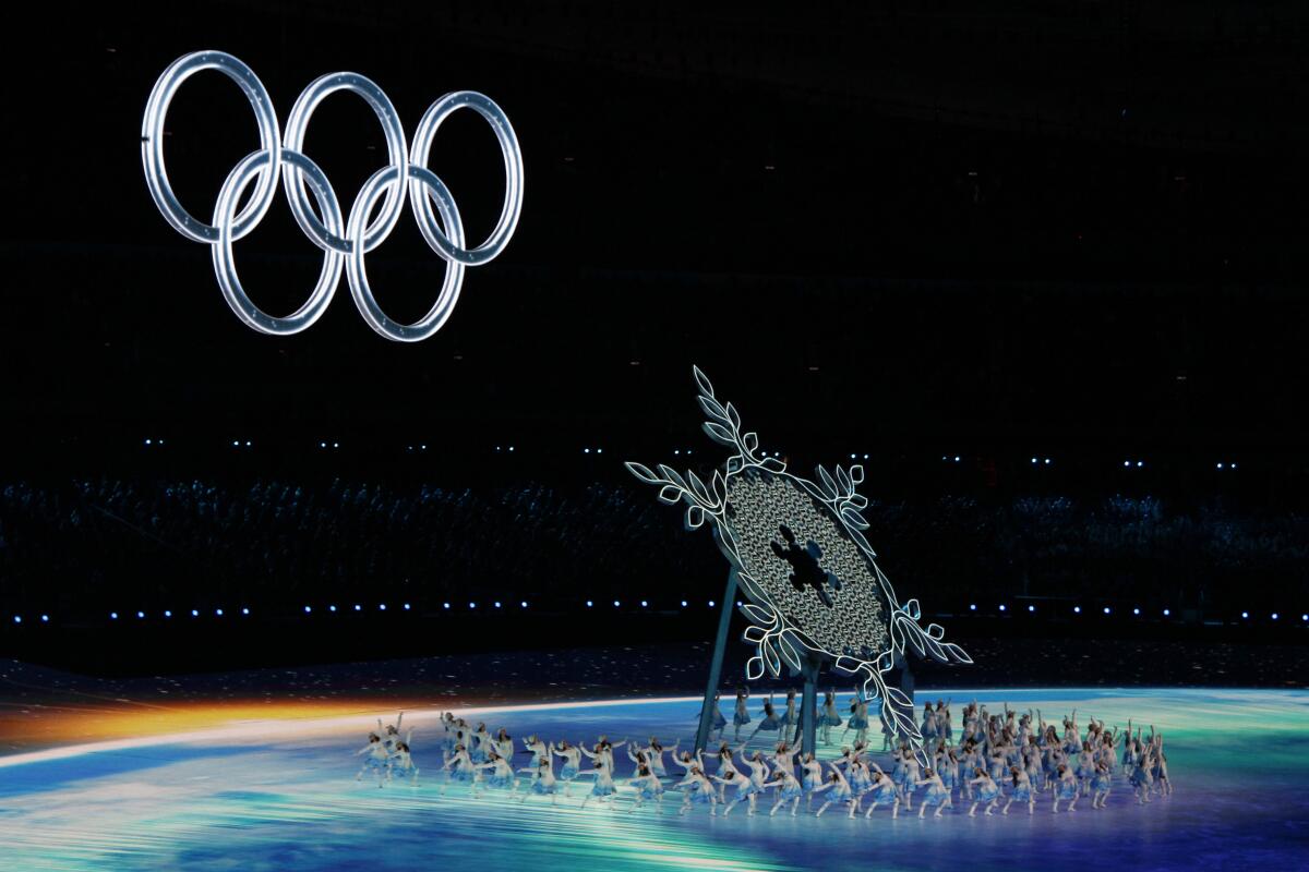 Performers dance as a giant snowflake rises under the Olympic rings during the 2022 Beijing Games opening ceremony.