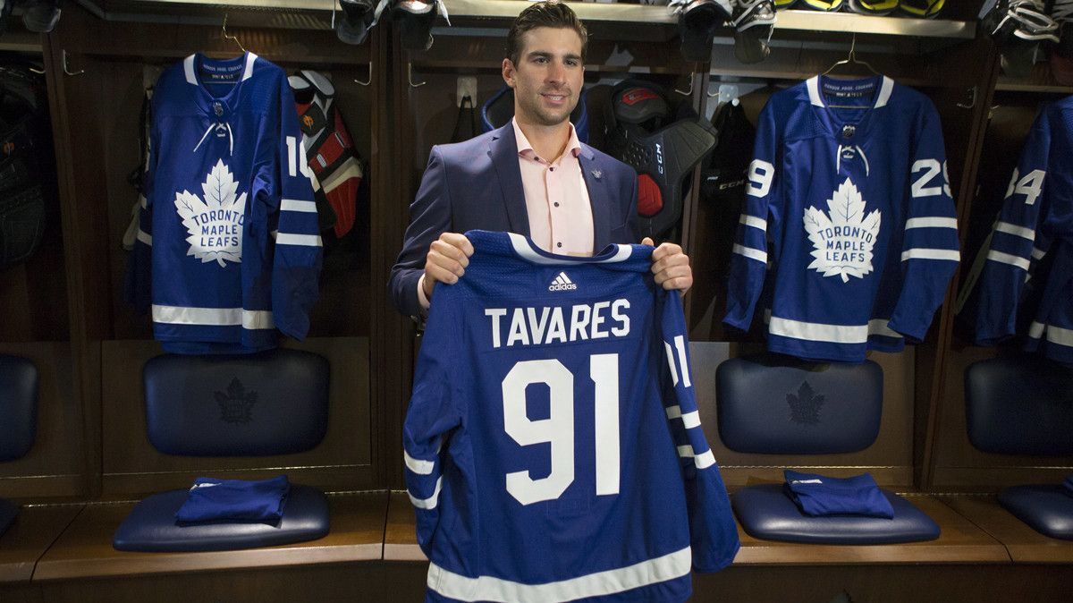 John Tavares holds up a Maple Leafs jersey in the team's locker room following a news conference in Toronto on Sunday, July 1.