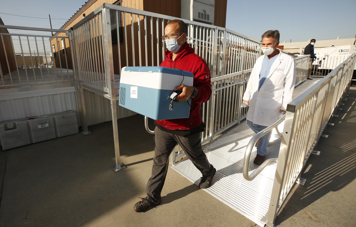 Emergency Medical Technician Lenny Fernandez carries a cooler specialized for the delivery of the Pfizer COVID-19 vaccine