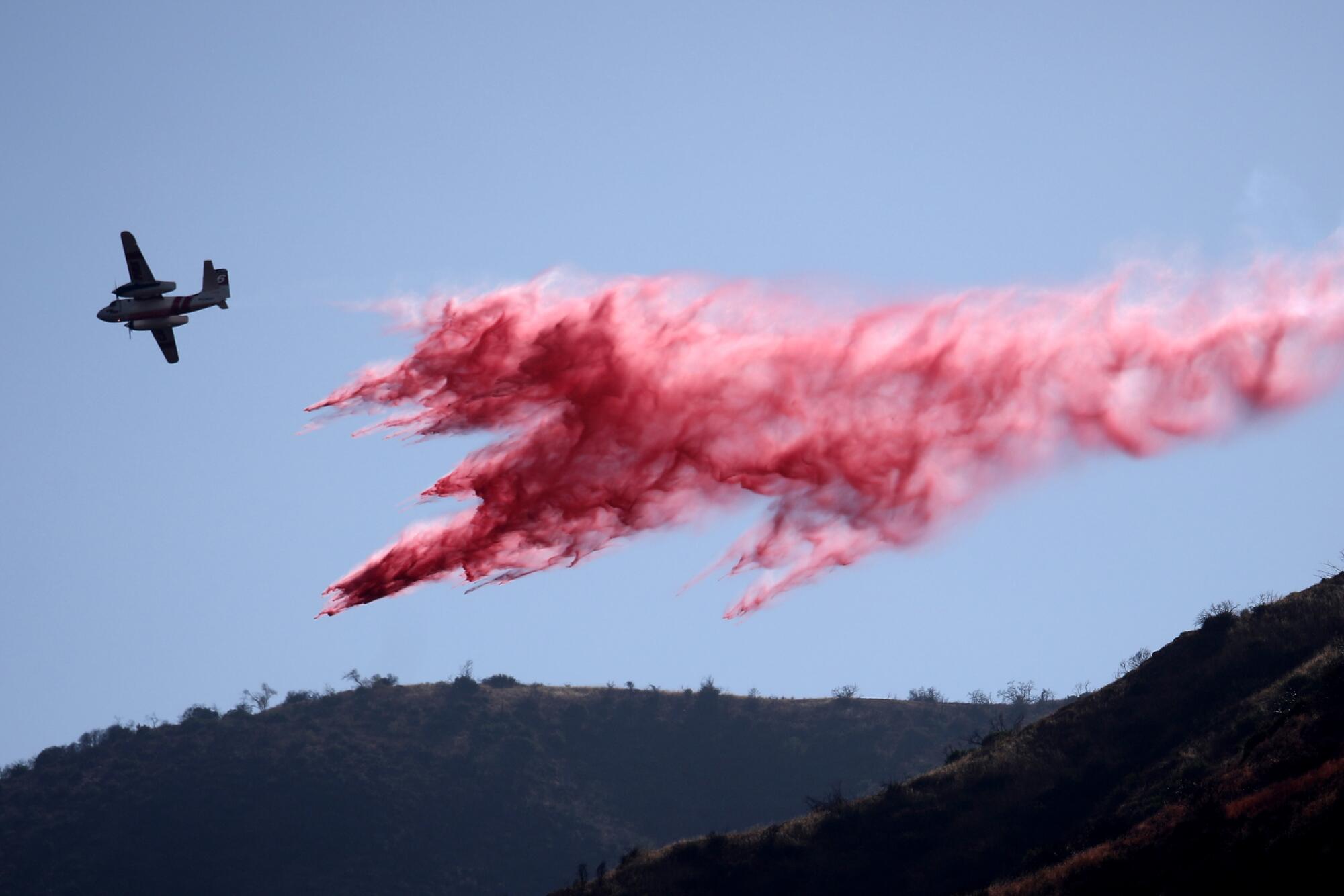 An air tanker banks away after dropping its load of pink fire retardant on the Gulch fire burning near the San Gabriel Dam.