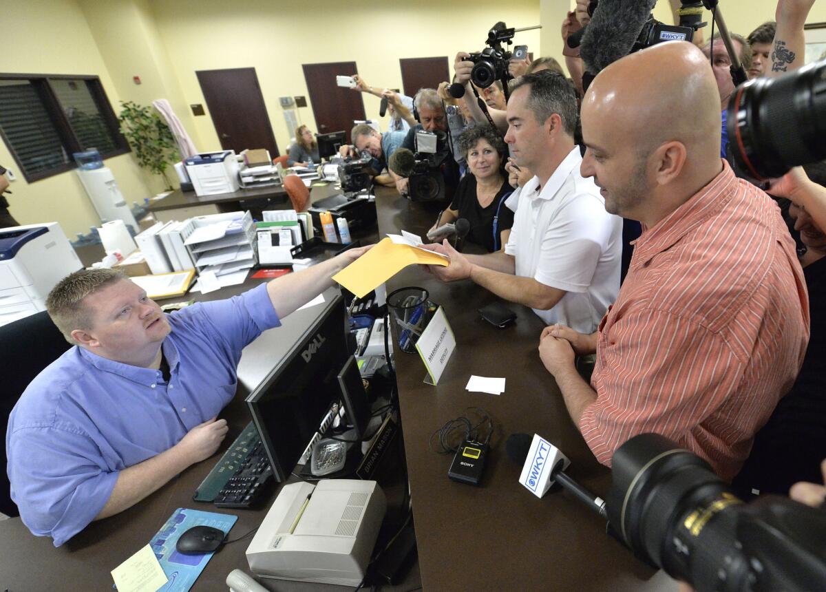 Deputy Rowan County Clerk Brian Mason, left, hands James Yates and William Smith Jr. their marriage license at the Rowan County Judicial Center in Morehead, Ky., on Sept. 4.
