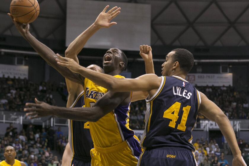 Lakers forward Brandon Bass goes up for a layup between Jazz forward Trey Lyles and center Rudy Gobert during the first half of Tuesday's preseason game.