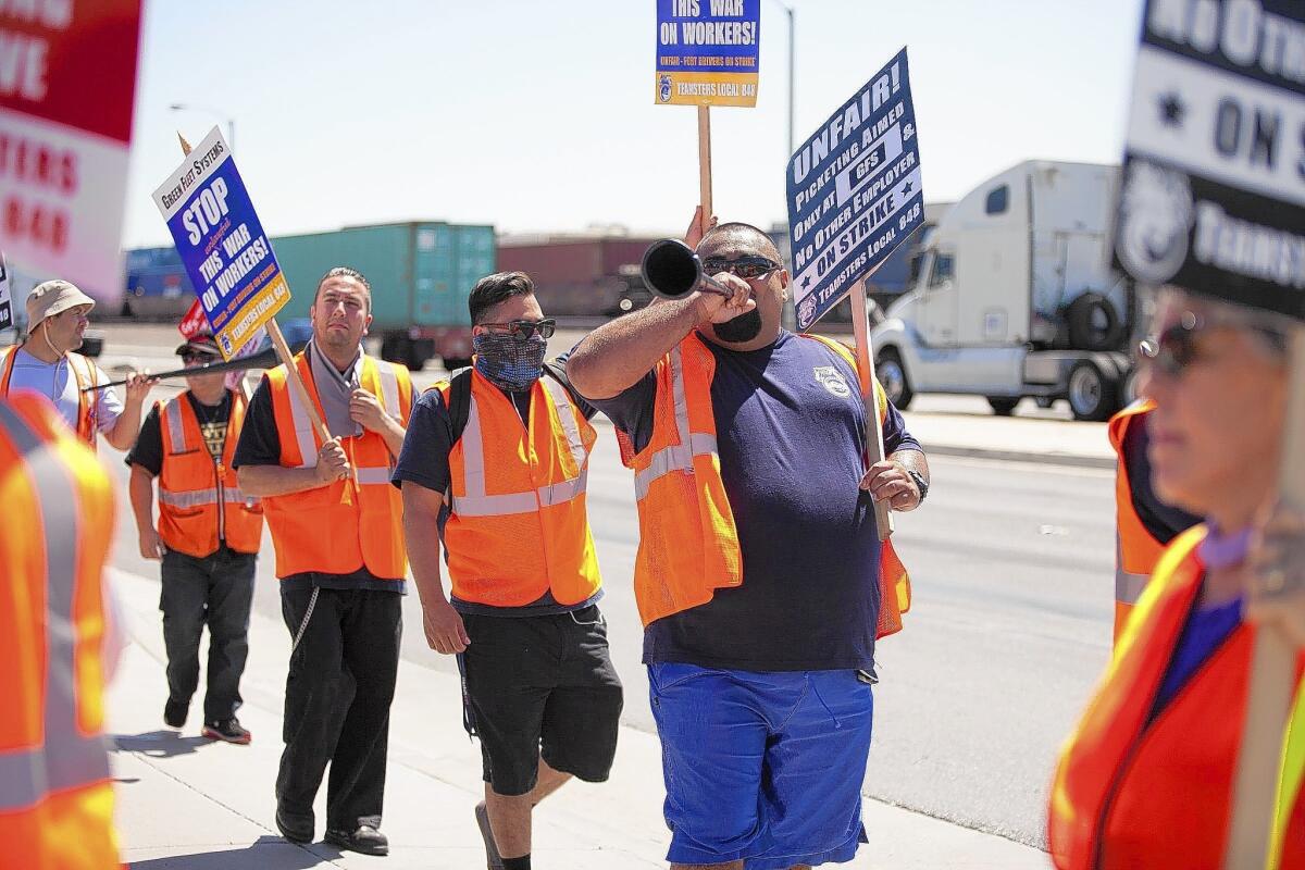 Picketers walk in front of the Green Fleet Systems building in Long Beach on Monday. The company is one of three targeted by port truck drivers in a labor protest.