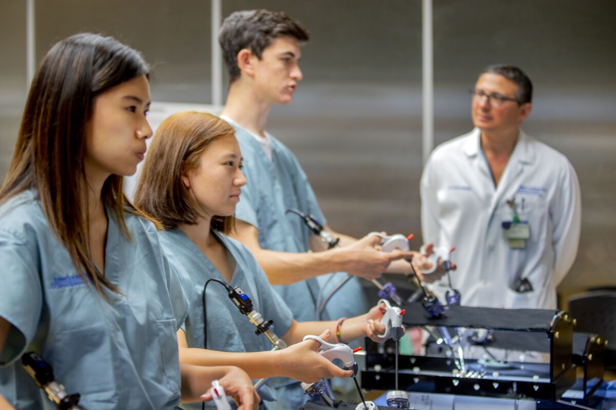 Students practice laparoscopic surgery technique while receiving pointers from Dr. Jaime Landman, right, the creator and chief supervisor of the summer surgery program at UC Irvine Medical Center.
