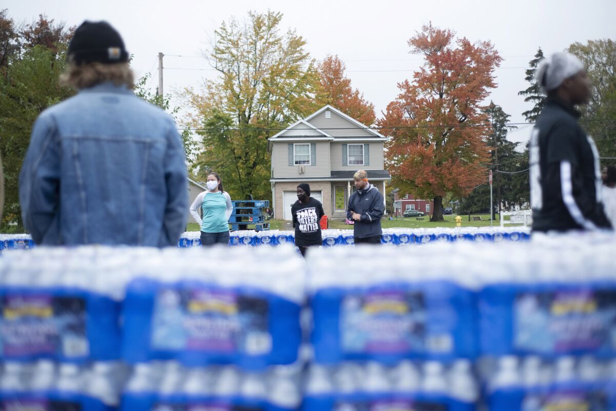 FILE - Volunteers help distribute cases of water bottles at God Household of Faith, Friday, Oct. 29, 2021, in Benton Harbor, Mich. Michigan and local officials have been targeted in a lawsuit over high levels of lead in Benton Harbor's drinking water. The lawsuit, filed this week in federal court, accuses the state and city of "deliberate indifference" in their response to the problem, which began to emerge in 2018. (Nicole Hester/MLIVE.com/The Grand Rapids Press via AP, File)