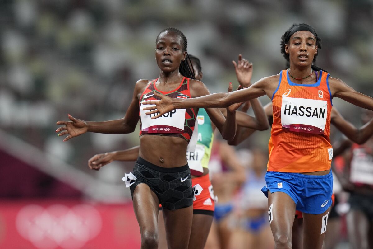 FILE - In this Friday, July 30, 2021 file photo, Sifan Hassan, of the Netherlands, right, crosses the finish line ahead of Agnes Tirop, of Kenya, left, to win a heat in the women's 5,000-meter run at the 2020 Summer Olympics, in Tokyo. Kenyan runner Agnes Tirop, a two-time world championships bronze medalist, has been found dead at her home in Iten in western Kenya, the country's track federation said Wednesday, Oct. 13, 2021. (AP Photo/Petr David Josek, File)