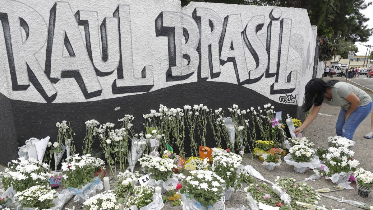 A woman leaves flowers one day after a mass shooting at the Raul Brasil state school in Suzano, Brazil, on March 14, 2019.