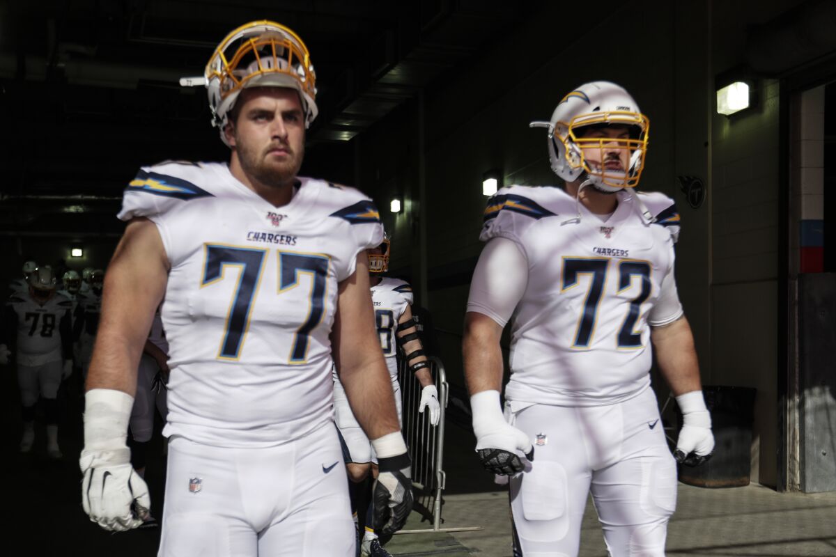 Chargers guards Forrest Lamp (77) and Ryan Groy get ready to take the field.