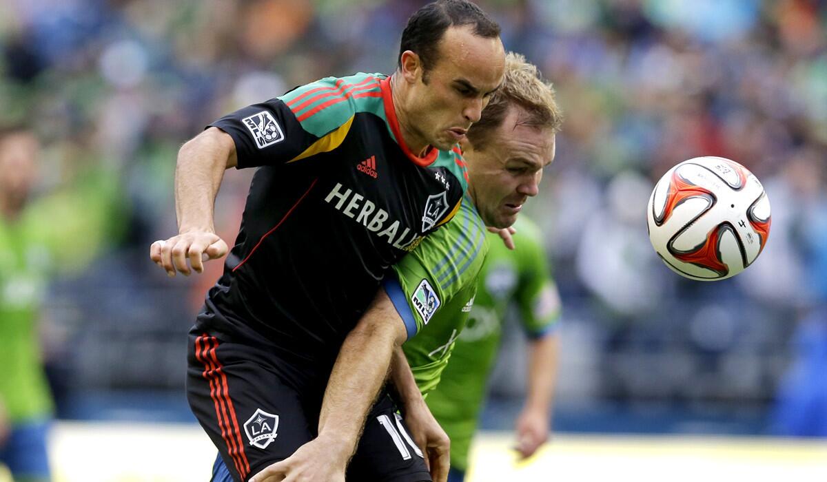 Galaxy midfielder Landon Donovan, left, tries to control the ball against Sounders defender Chad Marshall during play in the first half Saturday in Seattle.