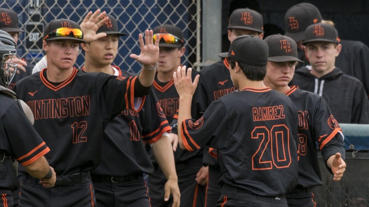 Dylan Ramirez gets high-fives from his Huntington Beach High teammates after getting out of a jam with runners on the corners in the bottom of the fifth inning at Newport Harbor.