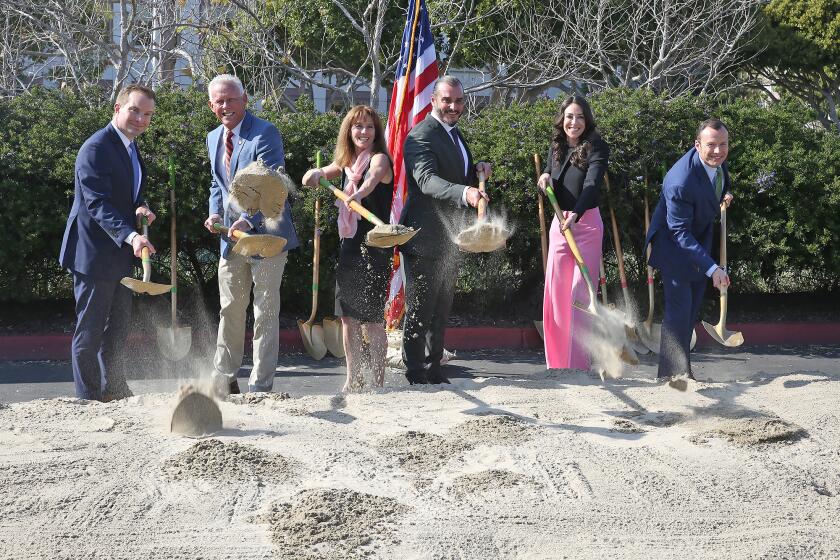 Council members Joe Stapleton, Brad Avery, Robyn Grant, Noah Blom, Lauren Kleiman, and Eric Weigand, from left, scoop a hill of sand as they join in a ground breaking ceremony for the new $23.7 million state-of-the-art lecture hall, to be named Witte Hall, at the Newport Beach Central Library on Tuesday in Newport Beach.