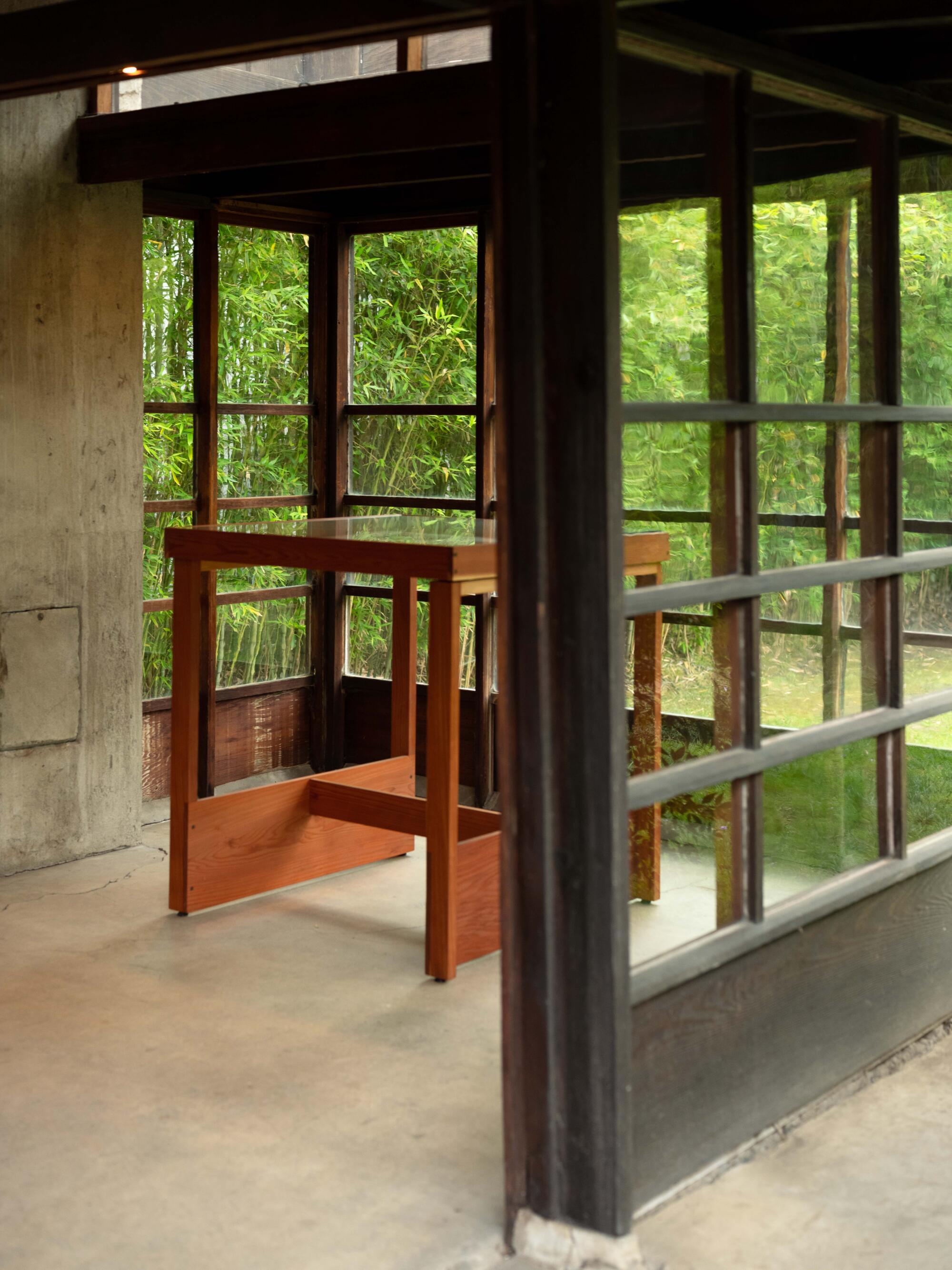 A window-lined studio area, with views of a garden, holds an exhibition vitrine.