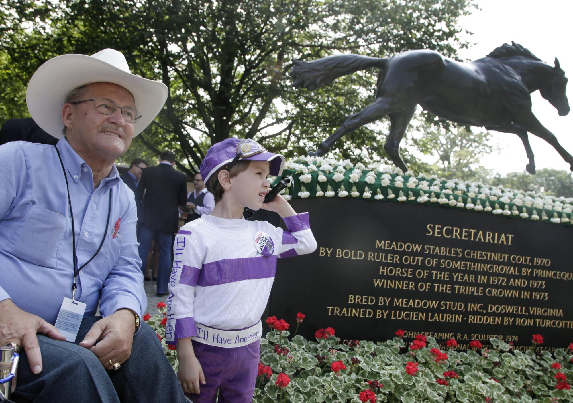 Retired jockey Ron Turcotte poses for photos with Kenny Foudy, 5, next to a statue of Secretariat.