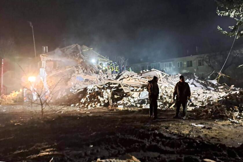 In this photo provided by Kharkiv regional Governor Oleh Sunyiehubov, firefighters examine the site of Russia's missile attack that hit an apartment building in Kharkiv Region, Ukraine, Thursday, Feb.15, 2024. (Kharkiv Regional Governor Oleh Sunyiehubov Office/ via AP)