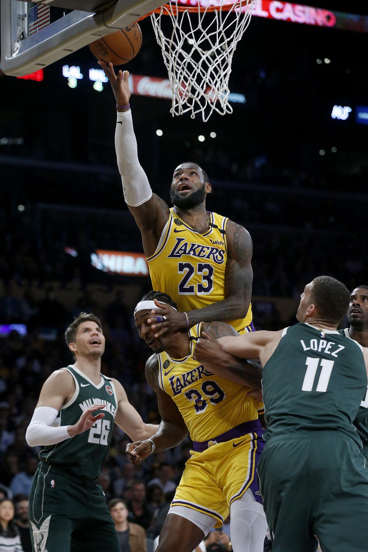 LeBron James scores a basket from Dwight Howard's back during the second half of the Lakers' victory over the Bucks on March 6 at Staples Center.