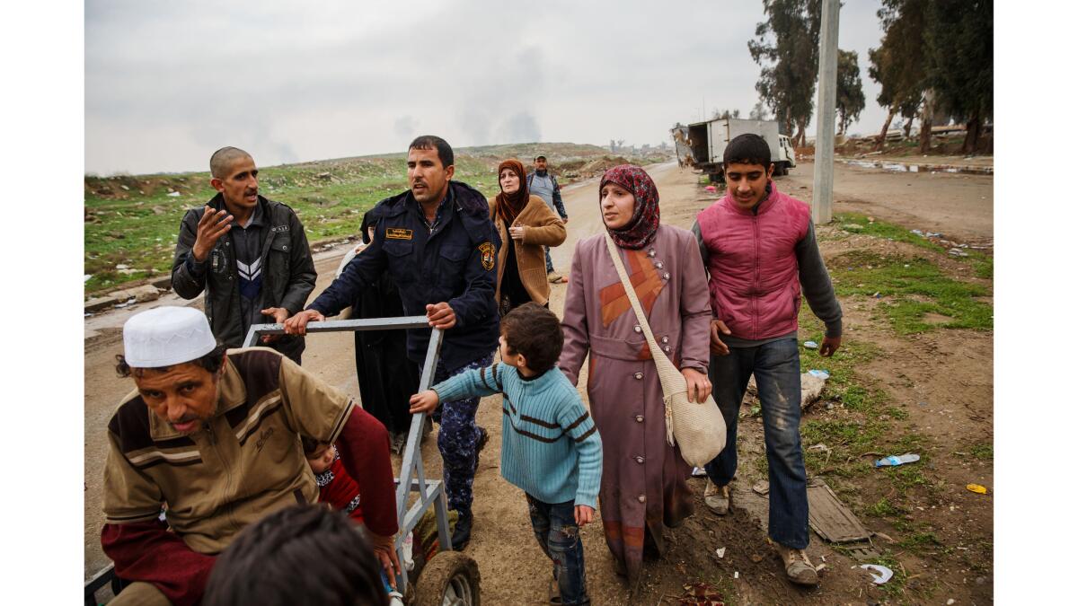 Under the threat of a sniper down the road behind them, residents flee the conflict in west Mosul.