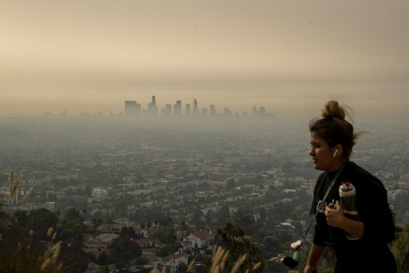 LOS ANGELES, CA - SEPTEMBER 17: A jogger runs along trail in Griffith Park as smoke from Southern California wildfires drifts over the L.A. Basin in a view from Griffith Observatory on Thursday, Sept. 17, 2020 in Los Angeles, CA. (Brian van der Brug / Los Angeles Times)