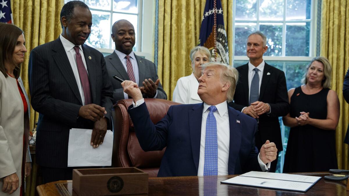 President Trump hands a pen to Housing and Urban Development Secretary Ben Carson, second from left, after signing an executive order establishing a "White House Council on Eliminating Regulatory Barriers to Affordable Housing" in Washington on June 25.