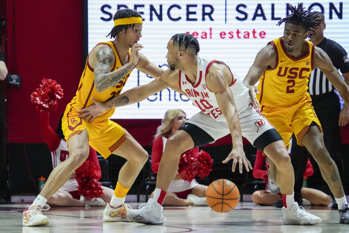Utah guard Marco Anthony, center, controls the ball between USC guards Tre White, left, Reese Dixon-Waters.