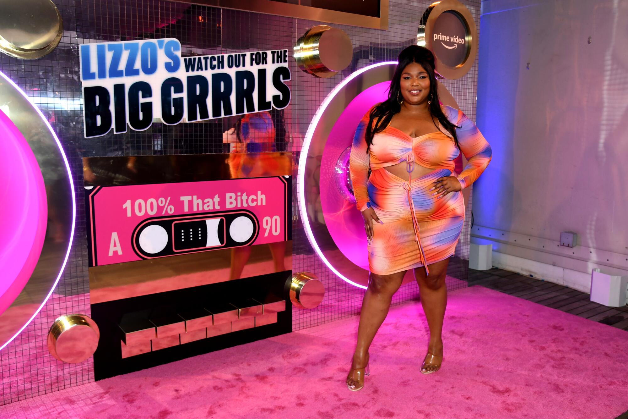 Lizzo stands in front of an advertisement for her TV show