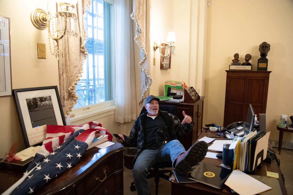 A man leans back in an office chair with his foot on the desk in a congressional office