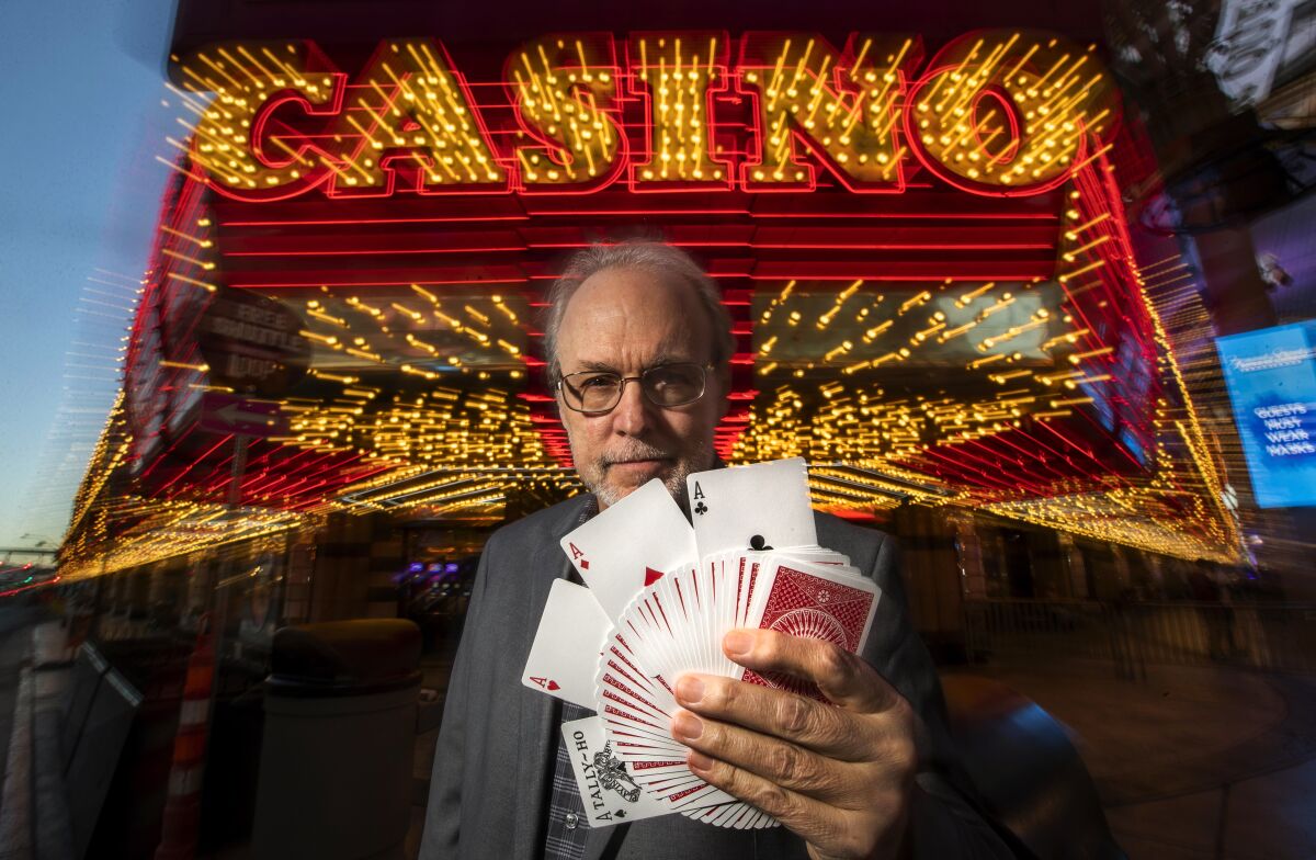 A man holds playing cards, fanned out, on Fremont Street in downtown Las Vegas.