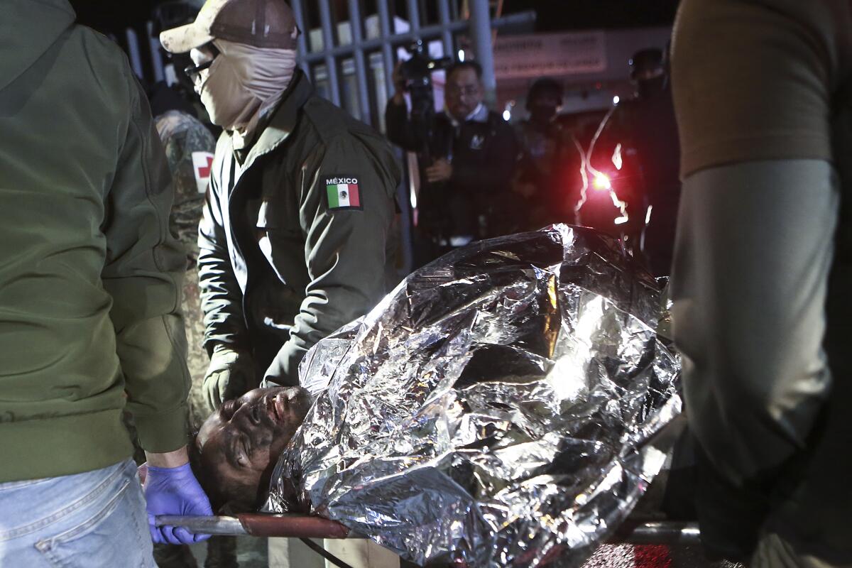 Paramédicos cargan a un migrante que resultó herido en un incendio 