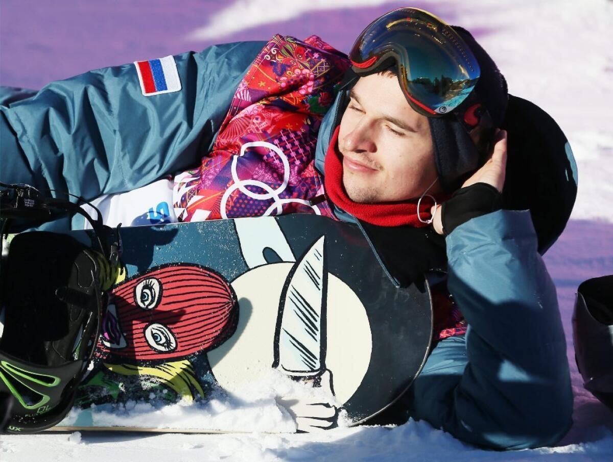 Alexey Sobolev holds his snowboard at the Olympics slopestyle qualification round at Russia's Rosa Khutor Extreme Park. The design on Sobolev's board has raised questions about his support for the controversial Russian band Pussy Riot.
