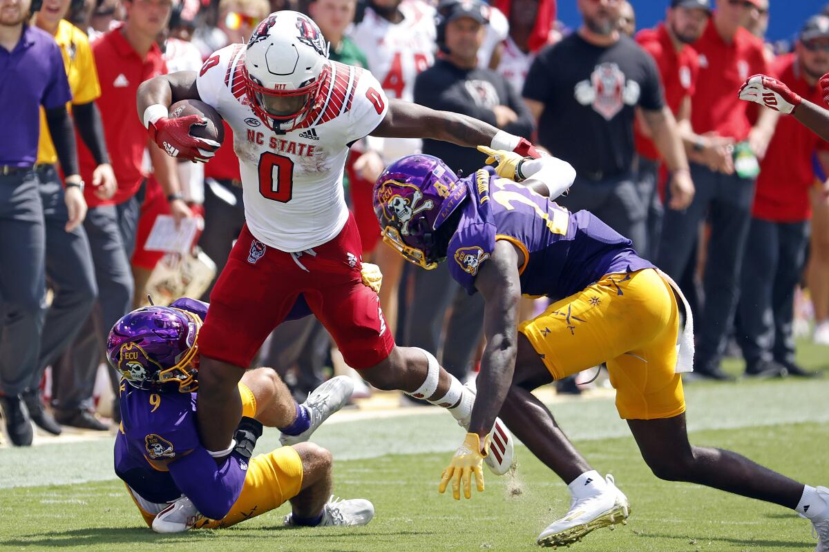 North Carolina State's Demie Sumo-Karngbaye tries to run the ball between East Carolina's Teagan Wilk (9) and Damel Hickman.