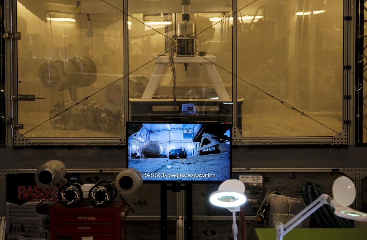 A robot seen through a window in a bin of dust.